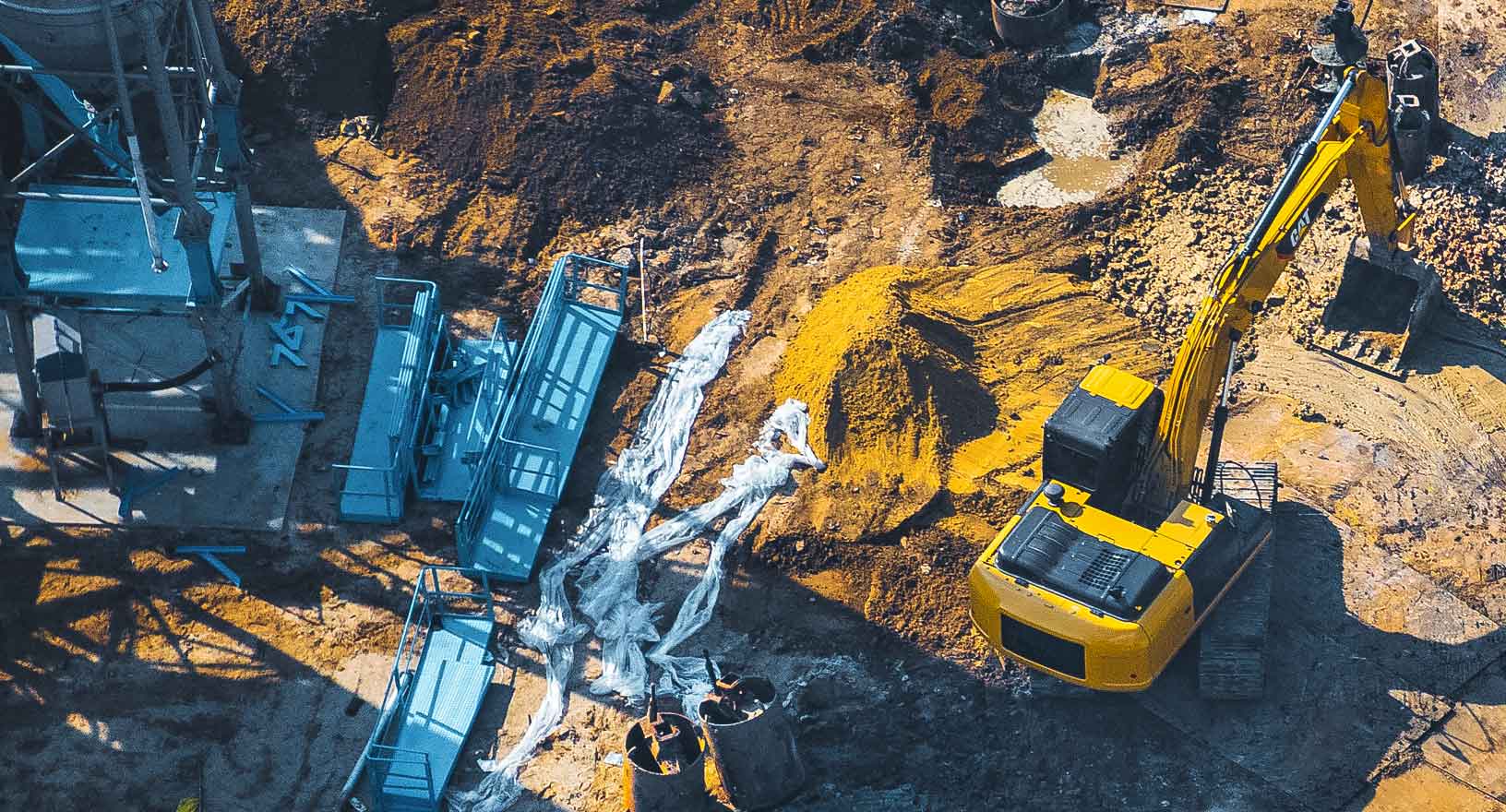 An excavator, cement truck and drilling machine work at a construction site to build new infrastructure.  