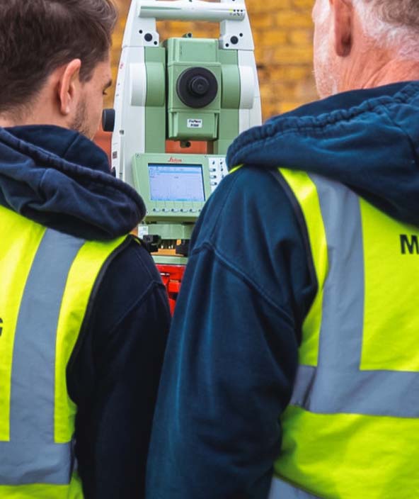 Zwei Vermessungsingenieure neben einer Totalstation