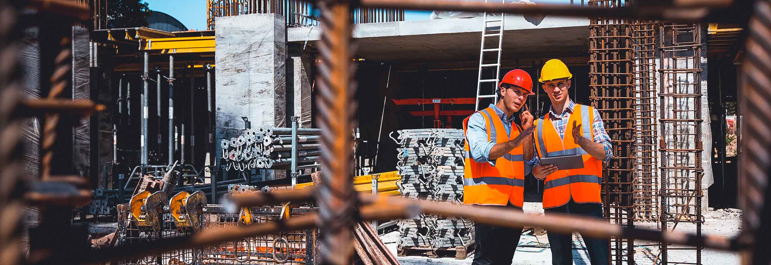 Workers in hard hats and safety vests speaking at a job site